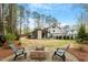 Beautiful backyard with a brick fire pit, Adirondack chairs, mature trees, and a partial view of the home's exterior at 302 Rutherglen Dr, Cary, NC 27511