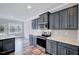 Charming kitchen featuring gray cabinetry, stainless steel appliances, quartz countertops, and hardwood floors at 358 Ashpole Trl, Clayton, NC 27520