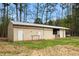 Exterior view of a white barn with multiple doors, nestled among trees at 3880 L Lawrence Trl, Graham, NC 27253