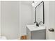 Modern bathroom with a gray vanity, white countertop, stylish mirror, and wood-look floors at 4815 Oak Park Rd, Raleigh, NC 27612
