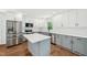 Bright kitchen features stainless steel appliances, white upper cabinets and gray lower cabinets, along with a large island at 4815 Oak Park Rd, Raleigh, NC 27612