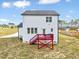 Back of white, two-story house with black roof, a small deck with red stairs, and a well maintained lawn at 62 Narmada Ct, Zebulon, NC 27597