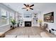 Bright living room with built-in shelving and decor around fireplace, ceiling fan, and wood laminate floors at 62 Narmada Ct, Zebulon, NC 27597