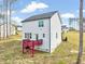 View of the home's rear exterior with a red deck and white siding, set on a partially grassy lot at 62 Narmada Ct, Zebulon, NC 27597