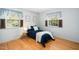 Comfortable bedroom featuring hardwood floors, a cozy bed, and natural light from two windows at 704 Emory Dr, Chapel Hill, NC 27517
