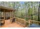 This covered back porch offers wooded views, wood floors, and a seating area at 8418 Wheatstone Ln, Raleigh, NC 27613