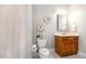 Bathroom with a decorative mirror, toilet, and single wooden sink vanity at 8418 Wheatstone Ln, Raleigh, NC 27613