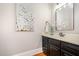 Chic powder room with a dark vanity, marble countertop, and decorative mirror at 8418 Wheatstone Ln, Raleigh, NC 27613