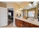 This bathroom features double sinks with stained cabinets and neutral-toned walls with an open view to the bedroom at 8437 Little Woody Ct, Zebulon, NC 27597