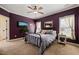This bedroom features a metal bedframe, carpeted floor, and aubergine-colored walls with neutral trim at 8437 Little Woody Ct, Zebulon, NC 27597