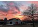 Exterior shot of the barn at sunset, highlighted with a beautiful fiery sky and silhouettes of trees at 97 Bailey Rd, Coats, NC 27521