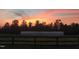 Greenhouse on a property with a wooden fence, silhouetted by a vibrant sunset at 97 Bailey Rd, Coats, NC 27521