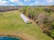 Aerial view of a greenhouse on a grassy property with trees and a blue sky at 97 Bailey Rd, Coats, NC 27521
