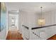 Bright hallway with hardwood floors, white railing, and decorative chandelier on the second level at 104 Perth Ct, Cary, NC 27511