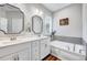 Bright bathroom featuring double sinks, white cabinets, and soaking tub at 1165 Shonele Ln, Stem, NC 27581