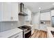 Close up of the white kitchen with stainless steel hood vent, herringbone backsplash, and modern gas range at 1165 Shonele Ln, Stem, NC 27581