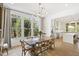 Elegant dining room with rustic wood table, modern chandelier, and large windows overlooking a lush, wooded view at 1200 Roosevelt Dr, Chapel Hill, NC 27514