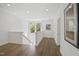 Bright hallway with hardwood floors and white wainscoting, showcasing the staircase and natural light from the window at 1200 Roosevelt Dr, Chapel Hill, NC 27514