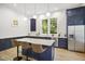 Modern kitchen with navy cabinets, stainless steel appliances, marble countertops, and island with seating for three at 1200 Roosevelt Dr, Chapel Hill, NC 27514