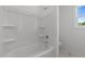 Bathroom with a shower-tub combo with white tiled walls and white flooring at 125 Summerlin Dr, Clayton, NC 27527