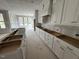 Elegant kitchen featuring white cabinets, an island with a sink, and a custom range hood at 125 Summerlin Dr, Clayton, NC 27527