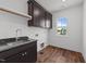 Laundry room features dark cabinets, sink with faucet and window providing plenty of light at 125 Summerlin Dr, Clayton, NC 27527