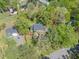 Aerial view showcasing a charming home nestled among mature trees with manicured landscaping and a nearby street at 1302 Hermitage Rd, Sanford, NC 27330