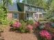 Charming home featuring lush landscaping, brick accents, and a welcoming front porch with white railings at 1302 Hermitage Rd, Sanford, NC 27330