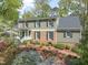 Charming two-story home with brick accents and manicured landscaping featuring vibrant azaleas and lush greenery at 1302 Hermitage Rd, Sanford, NC 27330