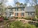Two-story home featuring a brick and wood facade, complemented by black shutters and a charming landscaped walkway at 1302 Hermitage Rd, Sanford, NC 27330
