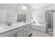 Bright bathroom featuring double sink vanity, large mirror, separate tub and shower, and tiled floor at 139 Pronghorn Deer Ct, Garner, NC 27529