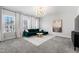 Well-lit living room with plush carpet, modern chandelier, and stylish green couch at 139 Pronghorn Deer Ct, Garner, NC 27529