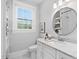 Bright bathroom with a white vanity, round mirror, and a window providing natural light at 1403 Wake Forest Rd, Raleigh, NC 27604