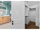 View of walk-in closet with shelving and hanging racks, next to modern bathroom with wood vanity at 1403 Wake Forest Rd, Raleigh, NC 27604