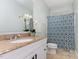 Well-lit bathroom featuring a granite vanity, decorative mirror, and shower with patterned curtain at 15101 Aiken Rd, Wake Forest, NC 27587
