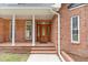 Close-up of a front entrance featuring a wooden door with glass accents and white support pillars at 15101 Aiken Rd, Wake Forest, NC 27587