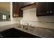 A close-up of a modern stainless steel double sink and granite counter tops with a white subway tile backsplash at 1523 Yarborough Park Drive, Raleigh, NC 27604