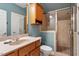This is a bathroom with a wooden cabinet, a sink, a toilet, and a glass door shower at 1525 Marshall Farm St, Wake Forest, NC 27587