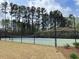Community tennis court surrounded by a black fence and tall pine trees at 1607 Willowcrest Rd, Durham, NC 27703