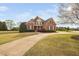 Charming brick two-story home with lush front lawn, mature trees, and a winding concrete driveway at 21 W Paige Wynd Dr, Angier, NC 27501