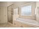 Main bathroom featuring soaking tub, glass enclosed shower, and natural light at 21 W Paige Wynd Dr, Angier, NC 27501