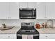 A close up of kitchen appliances featuring a microwave, stove top, and granite countertops at 211 Azalea Gaze Dr, Youngsville, NC 27596