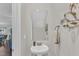 Stylish powder room with a pedestal sink, decorative mirror, and modern fixtures at 211 Azalea Gaze Dr, Youngsville, NC 27596