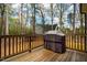 View of wooden back deck with grill overlooking wooded backyard at 215 Bonterra Way, Chapel Hill, NC 27516