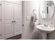 Cozy powder room with pedestal sink, round mirror, and charming white doors at 2456 Tonoloway Dr, Raleigh, NC 27610