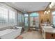 Luxurious bathroom featuring a large soaking tub, glass shower, double vanities, and travertine tile at 2922 Bells Pointe Ct, Apex, NC 27539