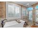 Bright and inviting bathroom with a soaking tub, glass shower, and large windows with shutter blinds at 2922 Bells Pointe Ct, Apex, NC 27539
