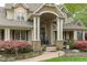 Inviting traditional home featuring a covered entryway with stone accents and professionally landscaped yard with mature trees and shrubbery at 2922 Bells Pointe Ct, Apex, NC 27539