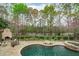 A backyard oasis featuring a stone-paved pool area with a hot tub, stone fireplace, and views of the lake at 2922 Bells Pointe Ct, Apex, NC 27539