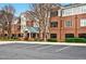 Brick apartment building featuring a covered entryway, manicured landscaping, and ample parking at 3700 Baron Cooper Pass # 104, Raleigh, NC 27612